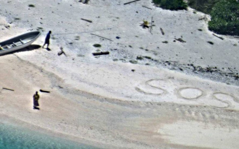 Uma foto do dia 25 de agosto que mostra os dois náufragos ao lado do SOS que desenharam na areia.